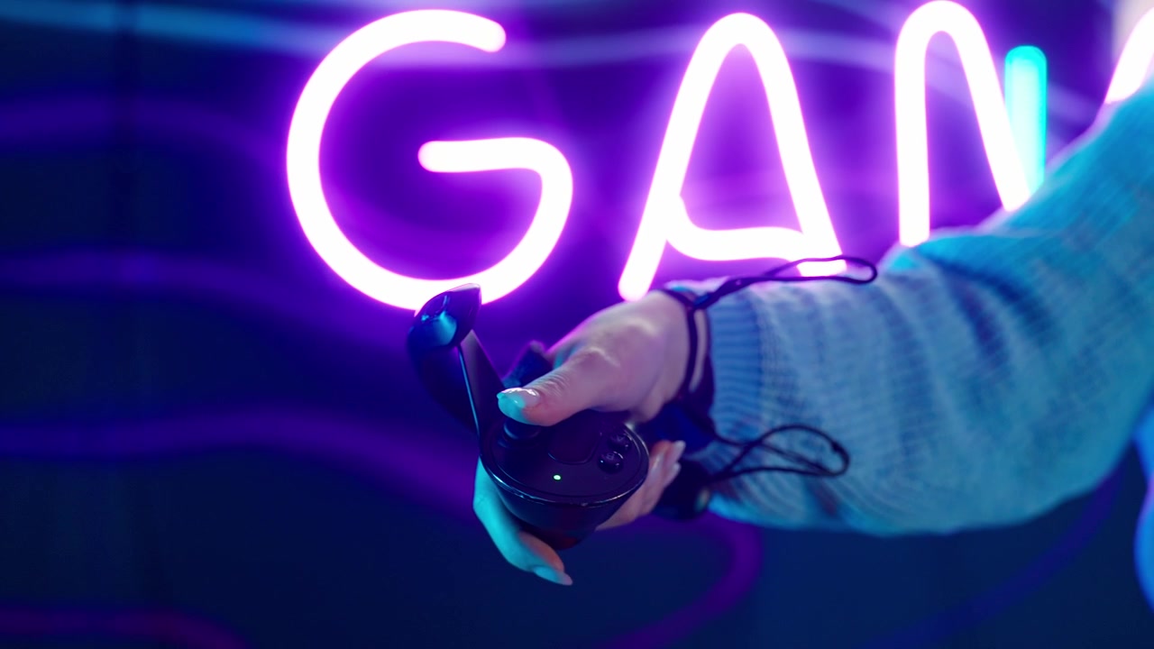Primo piano di una mano che tiene un controller VR contro un'insegna di gioco al neon