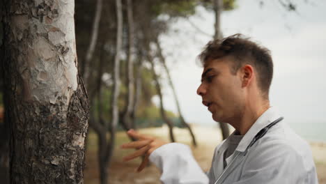 técnico habla con el tronco de un árbol como una persona loca en el parque