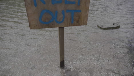 rising up to a wooden keep out sign on a lake