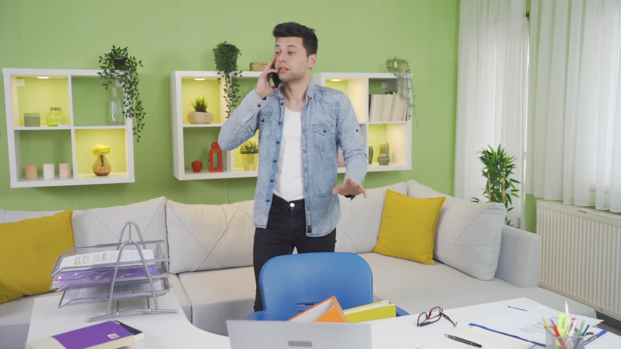 집에서 일하는 어색하고 불행한 젊은이가 손에 폴더를 떨어뜨리고 있습니다.