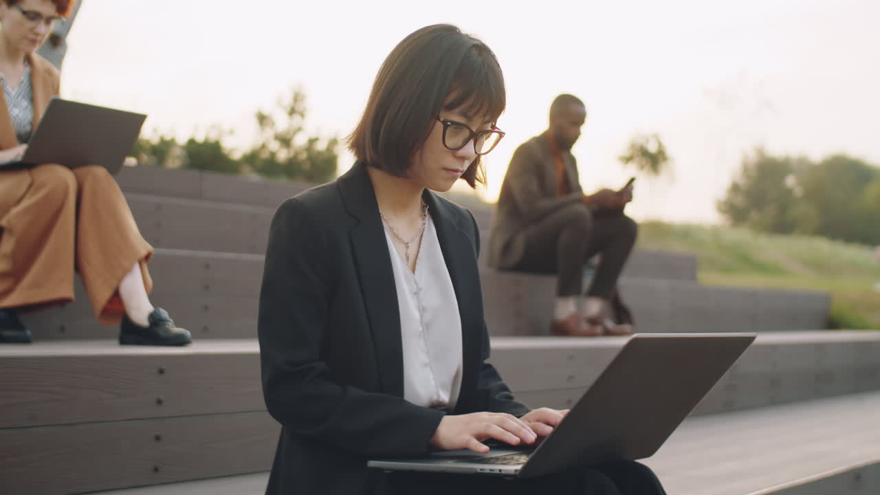 Donna d'affari asiatica che lavora al laptop nel parco