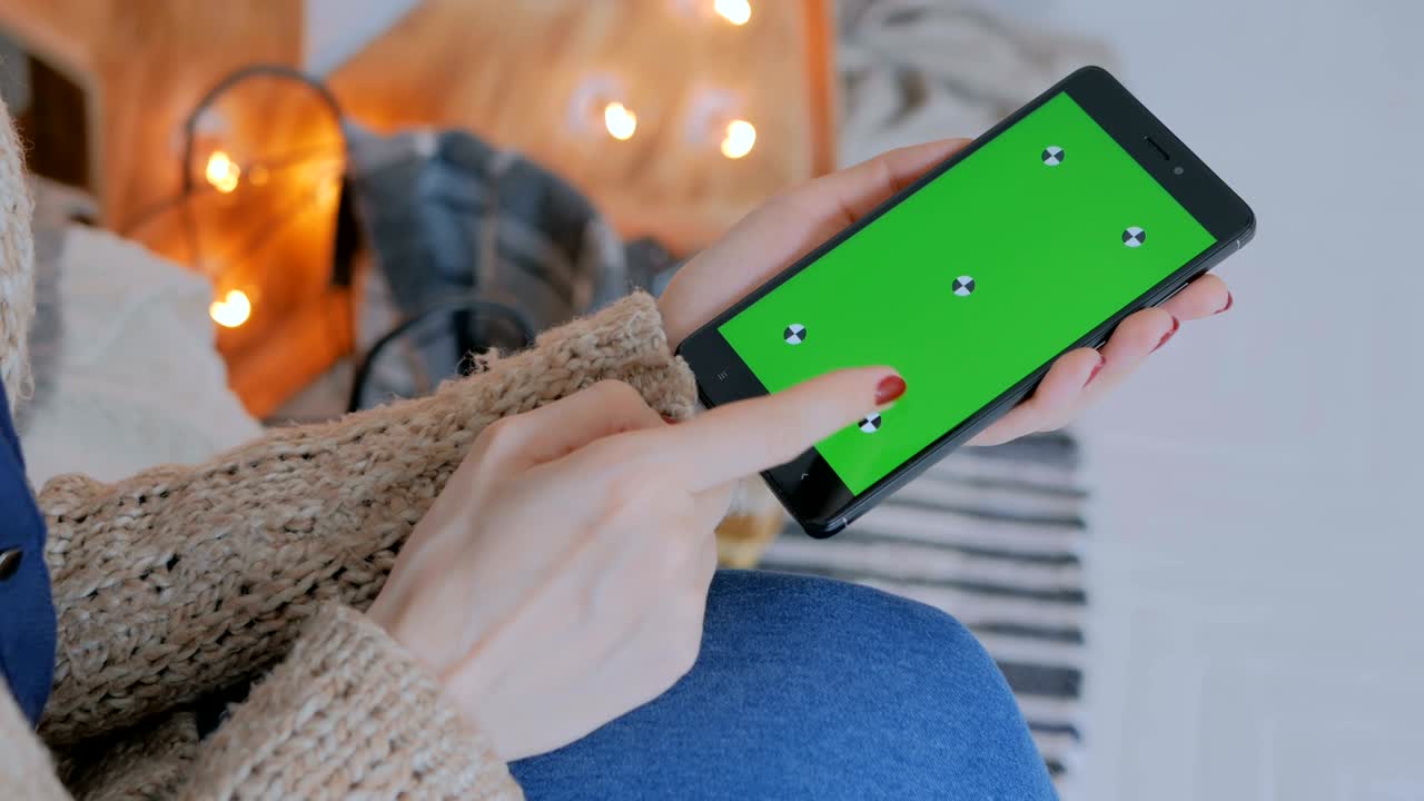 녹색 화면을 가진 스마트 폰을 사용하는 여성