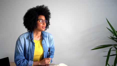 Positive-black-female-talking-with-person-and-taking-notes-in-notebook