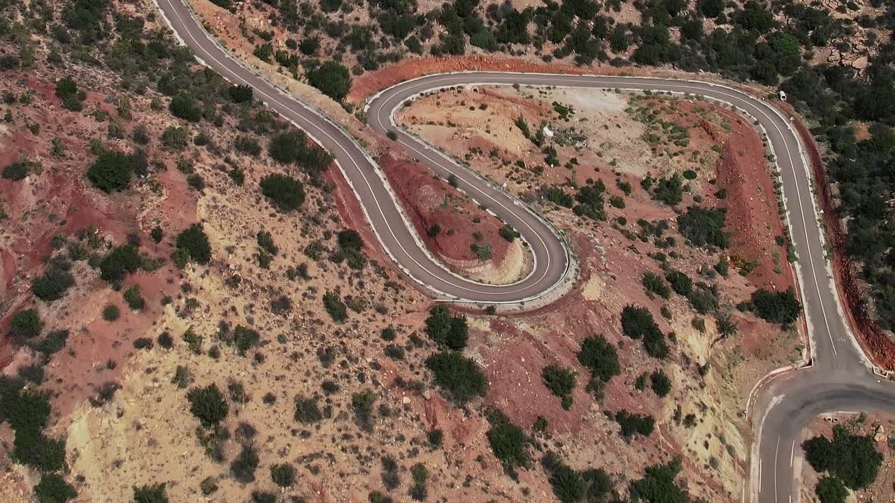 Strada tortuosa attraverso un paesaggio arido in Marocco ripresa dall'alto.