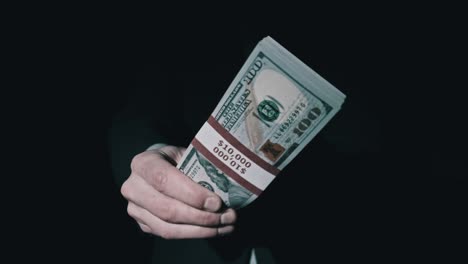 stack of 10000 american dollars in bundle in male hands on black background