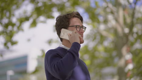 hombre barbudo con gafas hablando por teléfono inteligente al aire libre