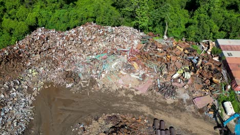 high-angle-pulling-drone-view-over-scrapyard-on-a-bright-sunny-day