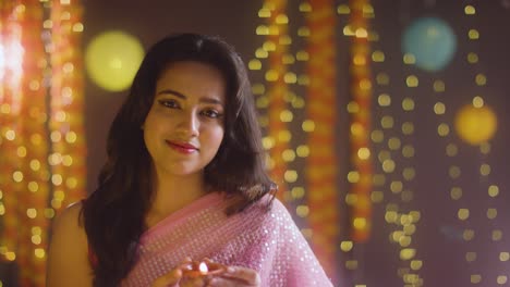 woman celebrating festival of diwali holding lit diya oil lamp towards camera 1