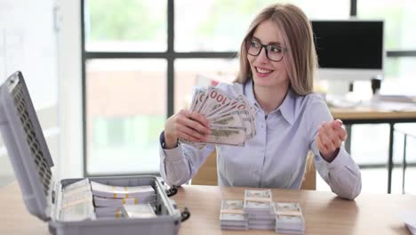 woman counting large stacks of money in an office