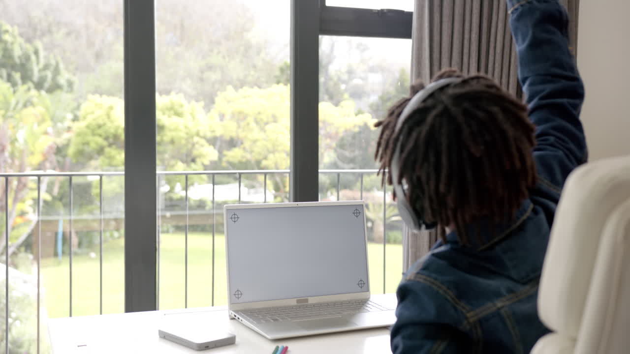 African american boy using laptop with copy space on screen for online lesson at home, slow motion
