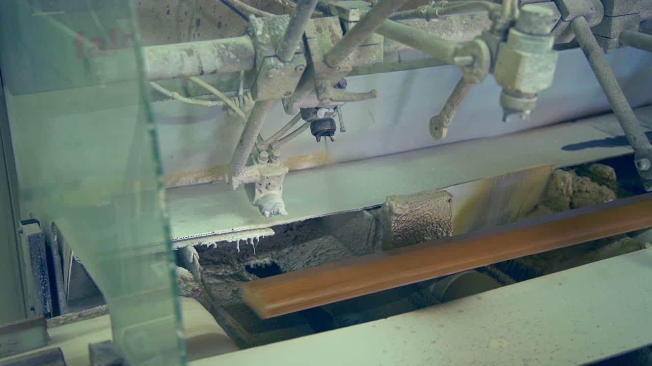 Varnishing machine at door production factory. Wooden plank is moved along the conveyor over the rollers.