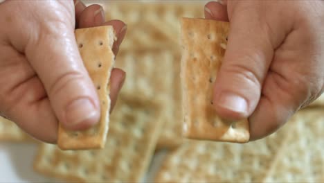 close up of female hands breaking a cracker in half