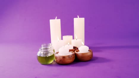 Sea-salt-in-wooden-bowl,-oil-and-candles-on-table