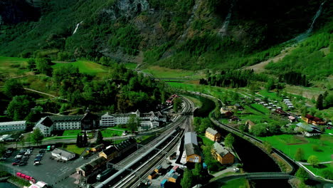 a smooth aerial shot of a railway station at a valley and a calm green landscape in norway