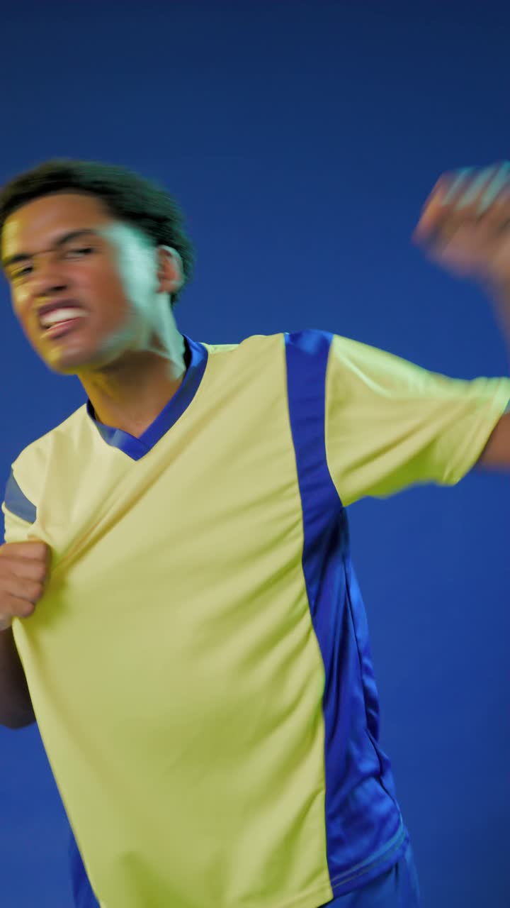 Video verticale: uomo africano che afferra una maglia gialla, tirandola per mostrarla, mostrando pantaloncini blu in studio