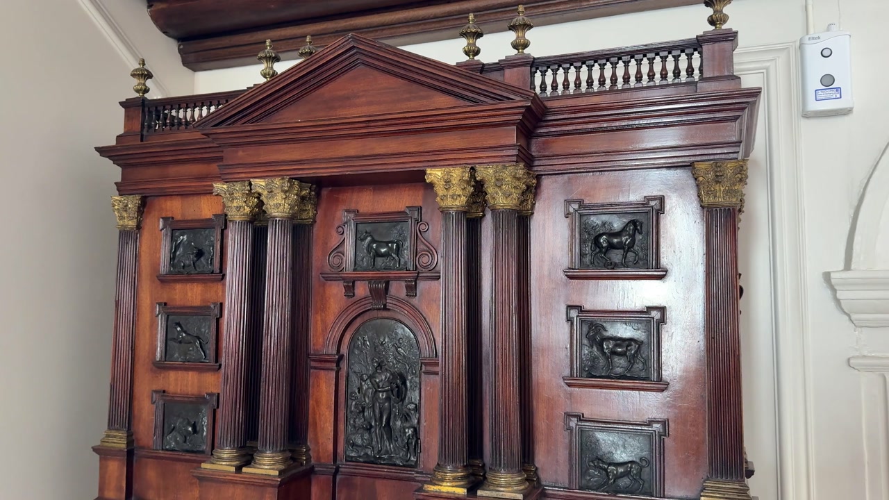 Ornate antique wooden cabinet with carved columns in museum interior