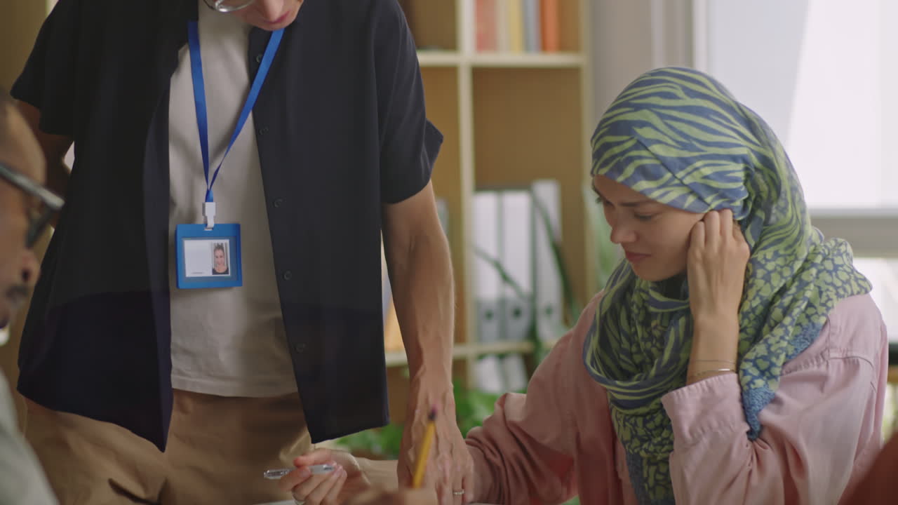 Teacher Helping Female Muslim Student during Lesson