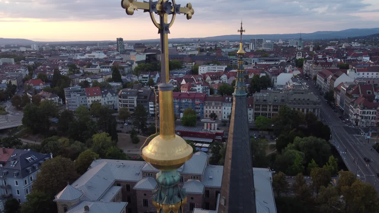 Drone revealing details of Church tower and cross on top of the cathedral in Freiburg im Breisgau during sunset with town view in background, Germany