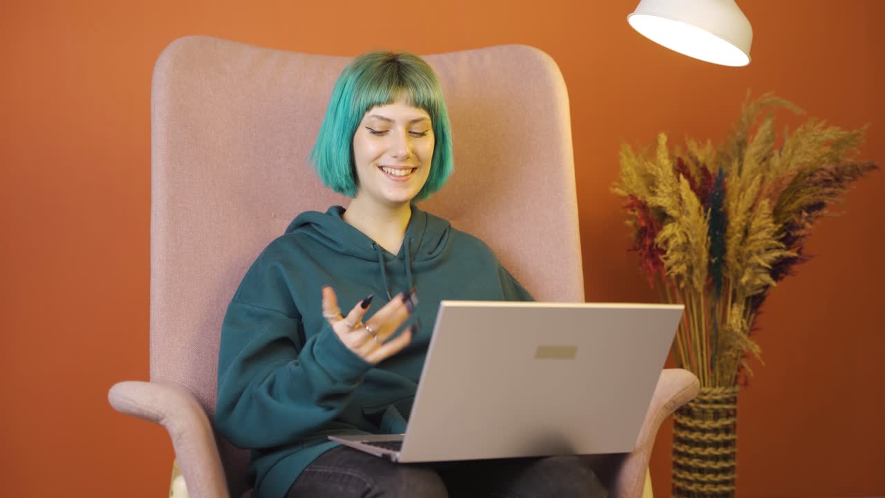 mujer joven mirando la computadora portátil haciendo un gesto positivo.