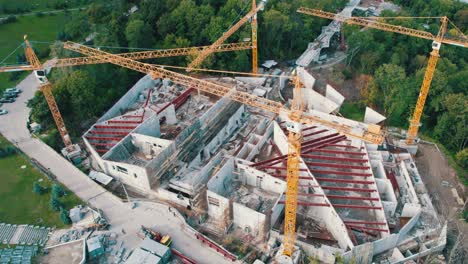 vista aérea construcción de un nuevo edificio con grúas de torre altas en área verde