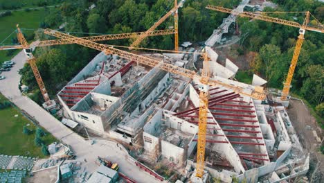 aerial view construction of a new building with high tower cranes in green area