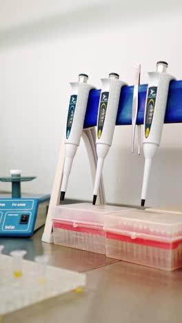 hand of medical worker checking vials of liquid. female's hand in sterile glove putting test tubes one by one into special machine in lab. vertical video