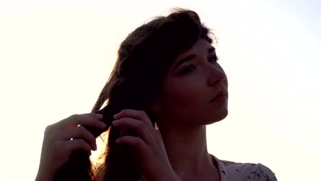 retrato de una adorable chica caucásica morena en un vestido rosa claro a la hora del amanecer