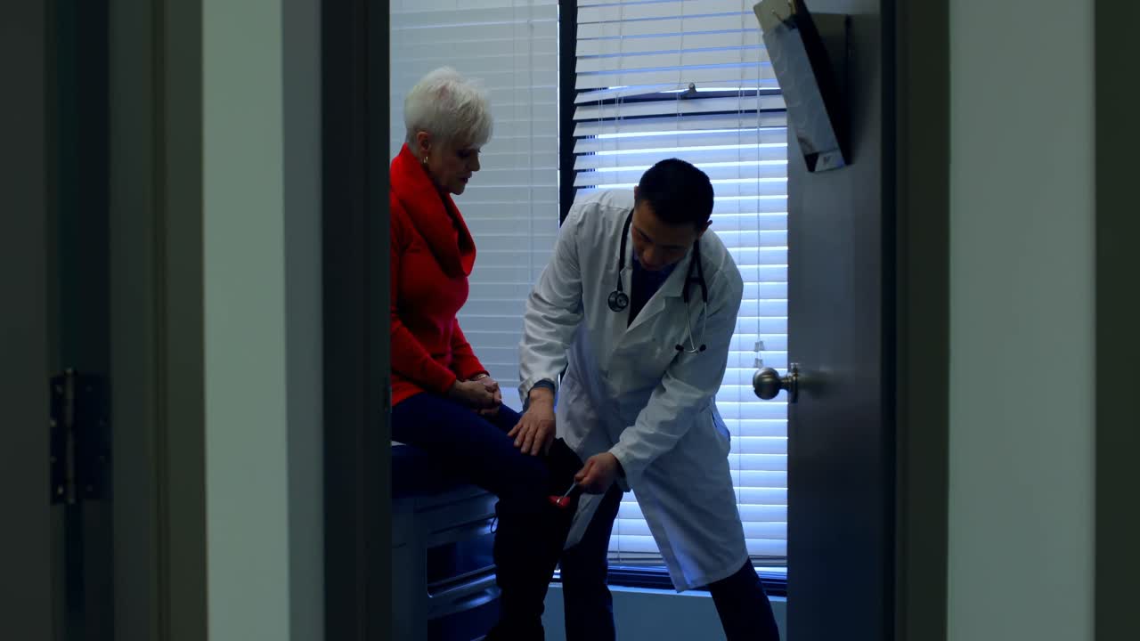 Young Asian male doctor examining a senior patient with reflex hammer in the clinic 4k