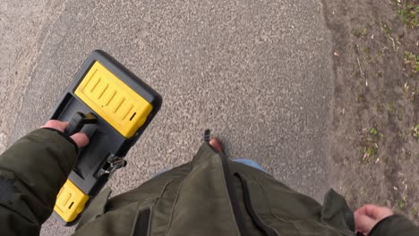 man carrying yellow toolbox, pov top down view