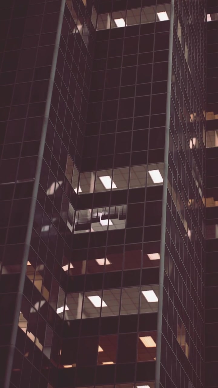 Vista de un moderno edificio de oficinas de noche con ventanas iluminadas.