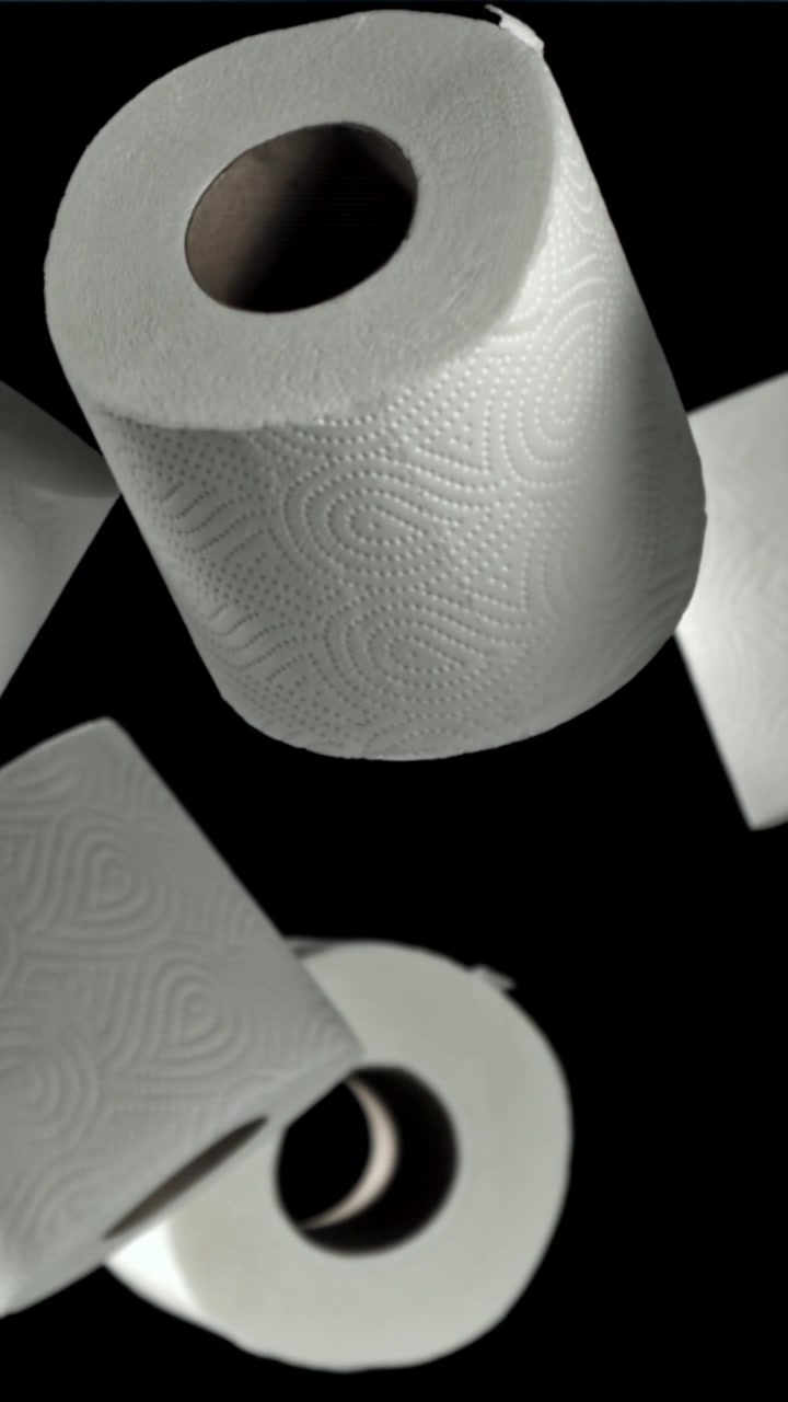 White Toilet Paper Rolls Floating in Slow Motion on Black Background