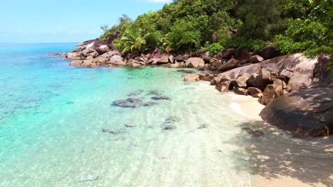 Drone-shot-near-white-sandy-beach,-turquoise-water-and-lush-vegetation-near-the-shore,-anse-major-beach,-Mahe,-Seychelles-30fps