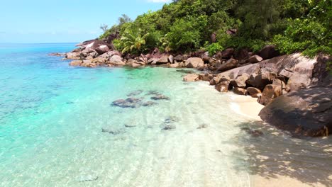 drone shot near white sandy beach, turquoise water and lush vegetation near the shore, anse major beach, mahe, seychelles 30fps