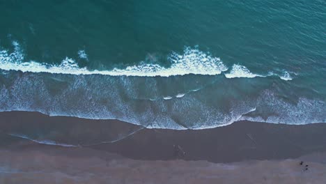 Toma-Aérea-De-Olas-Espumosas-Que-Se-Lavan-En-Una-Playa-De-Arena.