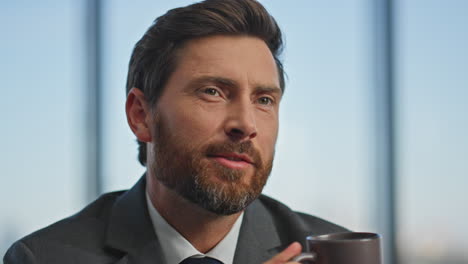 smiling worker drinking coffee resting at desk. closeup man hands typing laptop