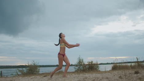 active sportswoman is playing beach volleyball young and slender athlete is striking ball slow motion shot