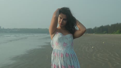 A-woman-is-standing-on-a-beach-wearing-a-blue-dress