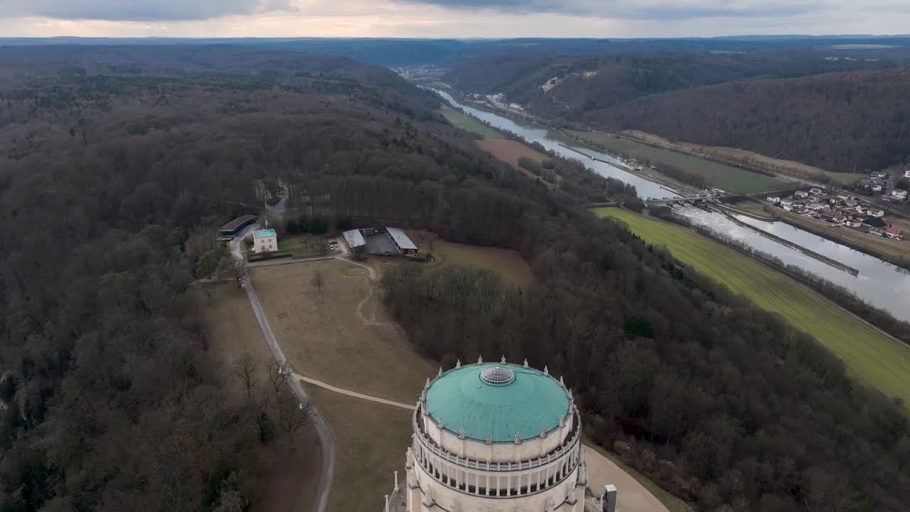 Stunning elevated footage of the Befreiungshalle, a prominent German landmark, majestically situated on a hilltop with the river and city in the background