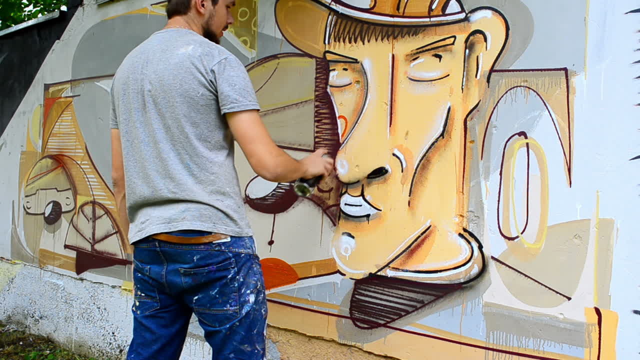 L'artista realizza graffiti su una recinzione. Disegno astratto