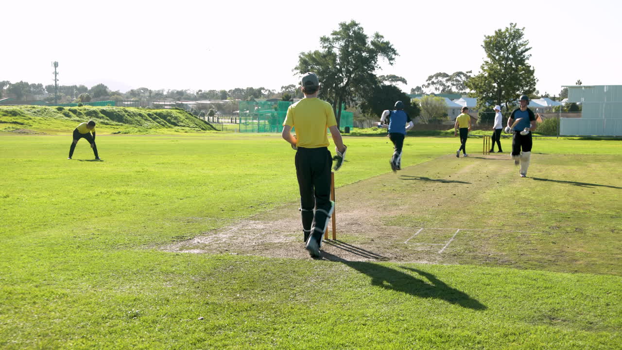 Cricket players running between wickets on sunny day at sports field