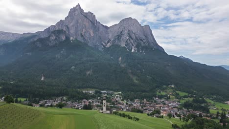 wonderful church tower in a valley on a green meadow with high mountains in the background, dolomites, italy, europe, drone