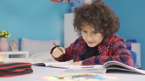 el estudiante de escuela primaria que hace la tarea en el escritorio está estudiando con placer.