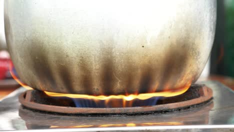 stainless steel pot with burnt sides on boiling water on fire, handheld view