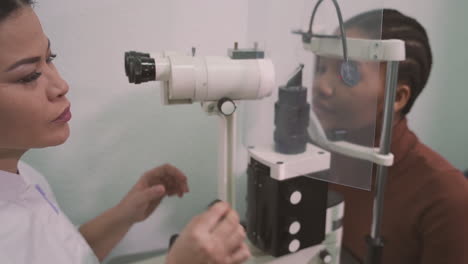 especialista en ojos femeninos hace una prueba de visión en una niña con una máquina de medición de la visión