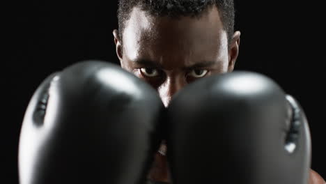 focused african american boxer ready to fight on black background