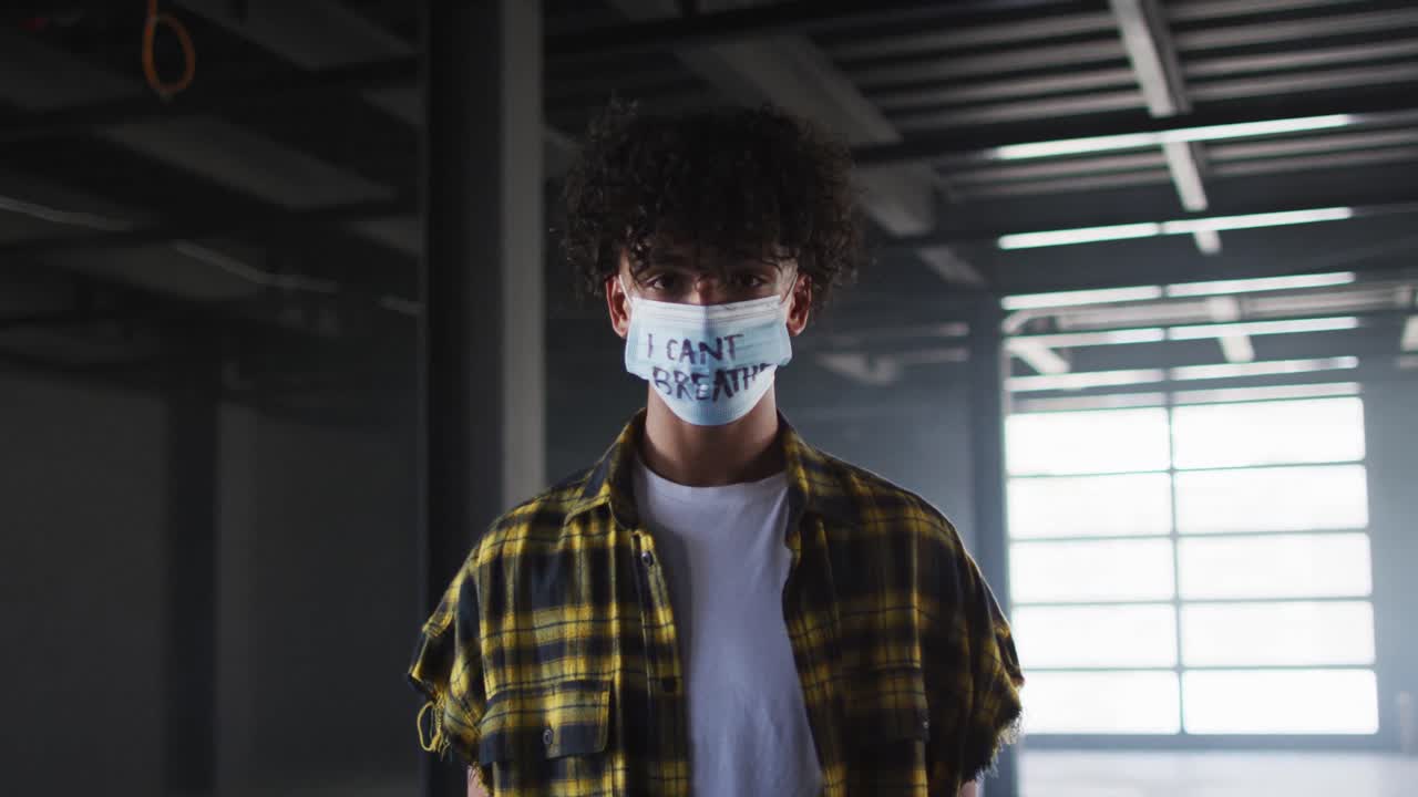 retrato de un hombre de raza mixta con una máscara de protesta en un garaje vacío