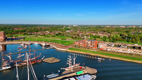 flying above the boats with sails down standing at the docks. stunning scenery of lelystad, the netherlands in the lush greenery at backdrop.