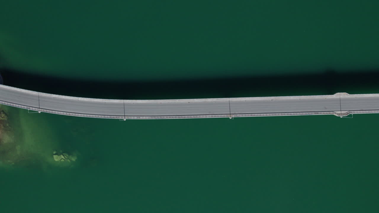 coches pasando por un puente a través de un lago