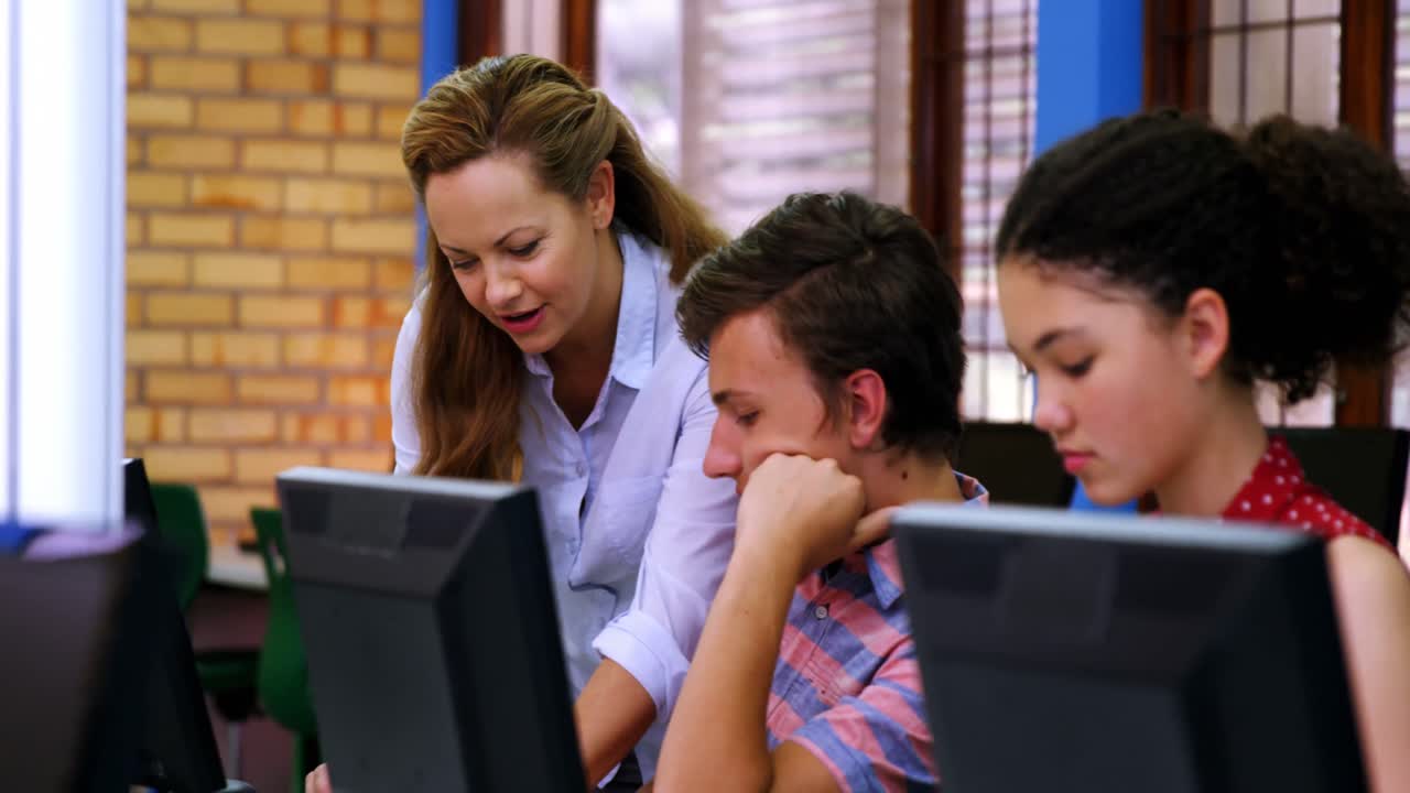 maestro ayudando a los estudiantes en la clase de computadora