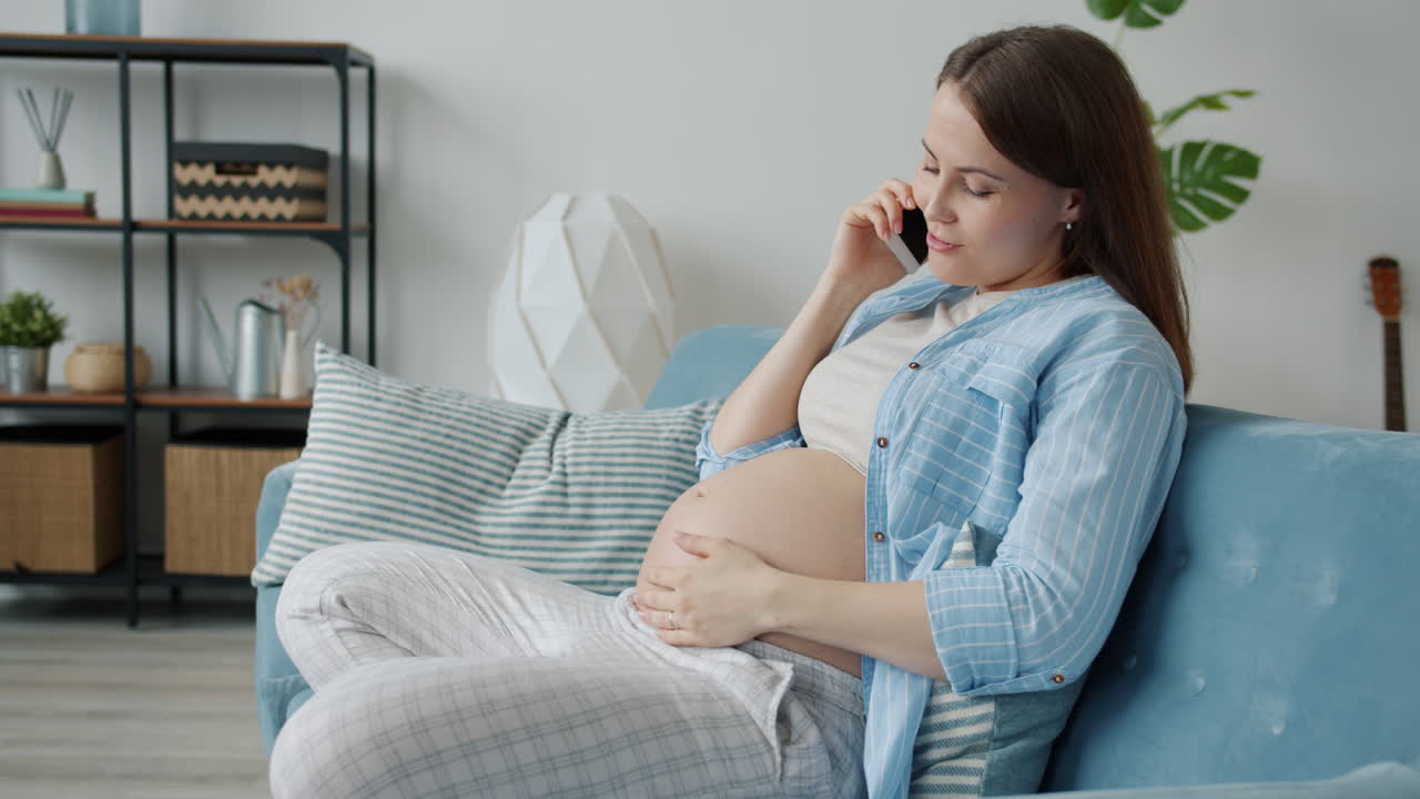 Pregnant woman talking on the phone at home